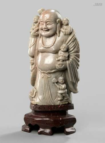 A SOAPSTONE FIGURE OF BUDAI WITH FIVE BOYS ON A STONE BASE, China, late Qing dynasty - Property from a Dutch private collection, acquired in Europe before 1990 - Very minor chips to the foot, minor wear