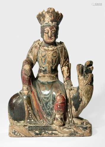 A WOOD FIGURE OF SIMHANADALOKESHVARA, CHINA, early Qing dynasty, seated in rajalilasana on his lion reclining on a shaped plinth, the right hand resting on the raised knee and the left placed on the lion, wearing a dhoti, scarf and bejewelled, his face displaying a serene expression with downcast eyes and his hair combed in a chignon secured with a tiara, his back with a closed cavity, traces of lacquer - Property from a German private collection, assembled in the 1970s and 80s - Wear, minor damage due to age