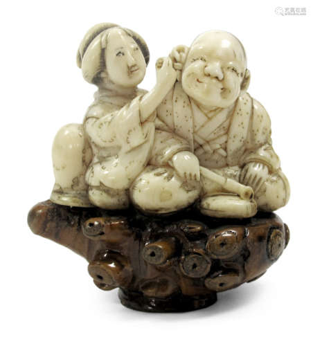 A CARVED IVORY OKIMONO OF A BIJIN SEATED NEXT TO A MAN CLEANING HIS EAR