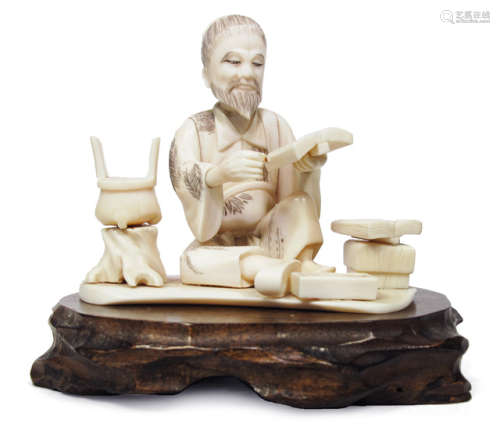 AN IVORY OKIMONO OF A SEATED SCHOLAR READING A BOOK