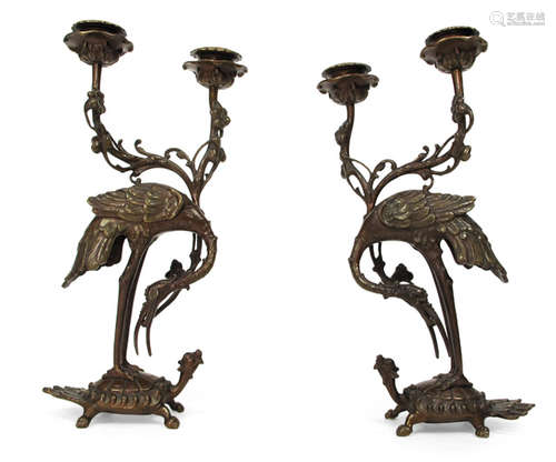 A PAIR OF BRONZE CANDLE HOLDERS IN SHAPE OF CRANES STANDING ON TOP OF MINOGAME