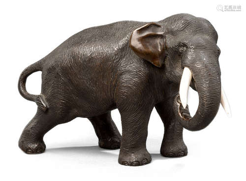 A BRONZE MODEL OF A WALKING ELEPHANT WITH IVORY TUSKS