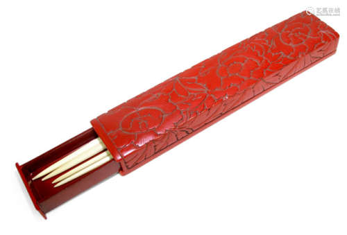 A CARVED RED LACQUER BOX DECORATED WITH PEONIES CONTAINING TWO PAIR OF IVORY CHOPSTICKS