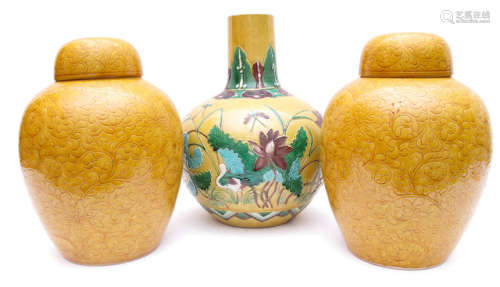 A PAIR OF YELLOW GLAZED PORCELAIN VASES AND COVERS AND A BOTTLEVASE DEPICTING LOTUS ON YELLOW GROUND