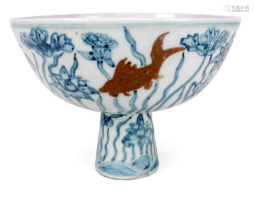 AN UNDERGLAZE BLUE AND WHITE STEMCUP DEPICTING LOTUS AND RED FISHES