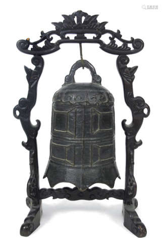 A BRONZE BELL IN A CARVED WOOD RACK