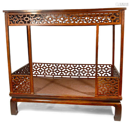 A BED WITH OPEN CARVED SIDES AND BASKETWORK