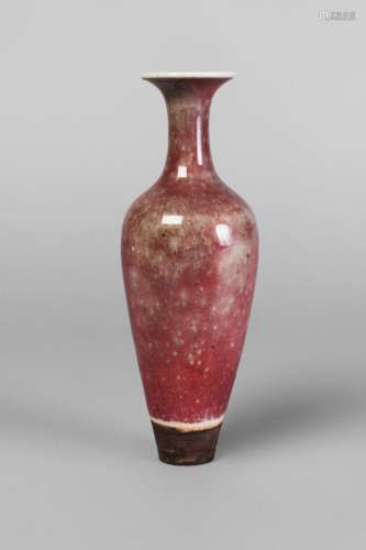 A Chinese porcelain peach bloom vase, Kangxi mark, 19th century, of slender form, with narrow neck and flared rim, the reddish-pink glaze suffused with green dots, underglaze blue six-character mark to base, 15.5cm high