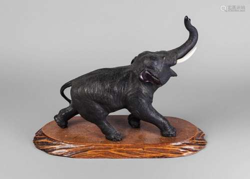 A Japanese bronze figure of an elephant, early 20th century, striding forward, with trunk raised, with ivory tusks, signed to underside, 36cm long, on wooden stand