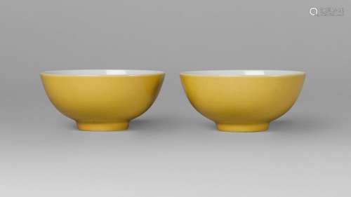 A pair of Chinese porcelain tea bowls, Yongzheng mark, Republic period, with imperial yellow glaze to the exterior, straight foot, underglaze blue six-character mark within a double ring to base, each with traces of paper collection label, 3.5cm high, 8.5cm diameter