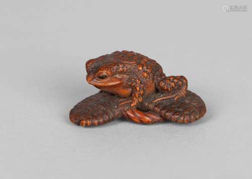 A Japanese boxwood netsuke of a toad, early 20th century, the toad carved crouching on a straw sandal, signed, 4.8cm long