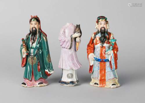 A pair of Chinese porcelain officials, Republic period, painted in polychrome enamels, one holding a ruyi sceptre, the other holding a scroll, 20cm high, and an 18th century famille rose figure, 19cm high (3)