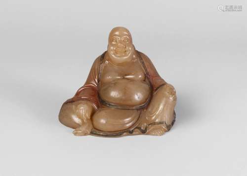 A Chinese soapstone carving of Budai Heshang, 18th/19th century, carved with left knee raised, his robe with traces of colour pigment, and finely engraved with floral motifs, with typical laughing expression, 7cm high