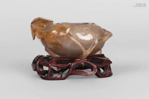 A Chinese agate water pot, late 19th century, carved with leafy foliage throughout, on fitted hardwood stand, 7cm high, 10.5cm long