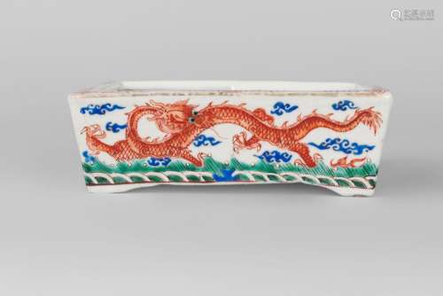 A Chinese porcelain rectangular brushwasher, iron red six character Qianlong mark but mid-19th century, painted with dragons amidst cloud wisps above crashing waves, 19cm wide, 13cm deep, 6cm high