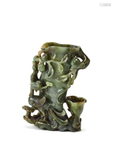 A Chinese spinach jade vase, 18th/19th century, finely carved as a phoenix with a lingzhi sprig in its mouth beside a peach tree trunk, with branches bearing six peaches, 13cm high