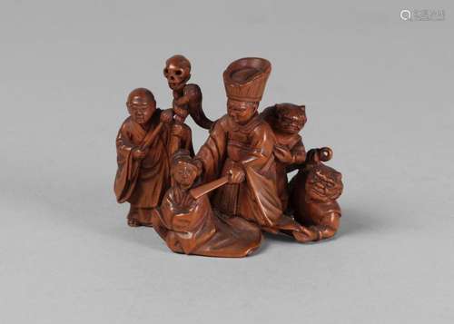 A Japanese boxwood okimono, mid 19th century, finely carved as a priest punishing a kneeling figure, watched by an assistant and two oni, signed, 8cm wide, 5.5cm high