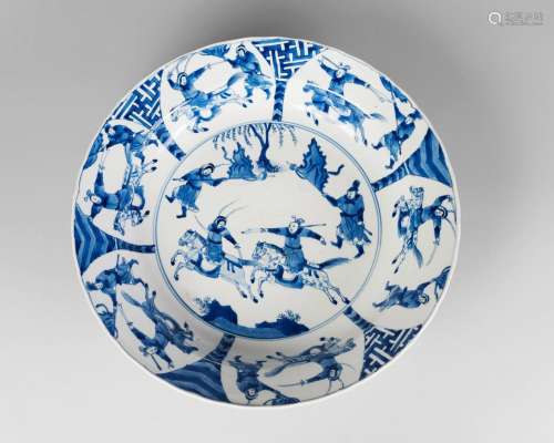 A large Chinese porcelain bowl, Chenghua mark, Kangxi period, painted in underglaze blue to the central medallion with warriors on horseback, inside a border of six panels depicting warriors, underglaze blue six-character mark within a double ring, 35cm diameter