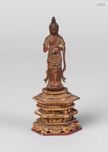 A Chinese carved wood miniature figure of Buddha, 18th/19th century, carved standing, with gilt decorated flowing robes, on stepped hexagonal base,