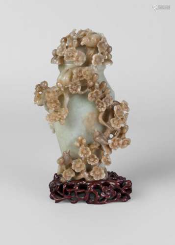 A Chinese green hardstone vase and cover, 20th century, profusely carved with birds perched on blossoming prunus, on fitted hardwood stand, 22cm high