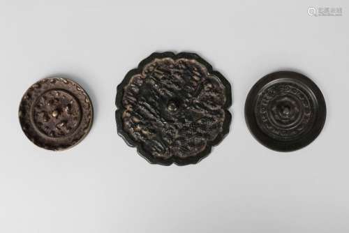 Three Chinese bronze mirrors, late Qing dynasty, one with barbed border and cast with figures, one with 'Beast and Grapes' design, the third with 'eight arcs' design, 7cm, 10.5cm and 8cm diameter