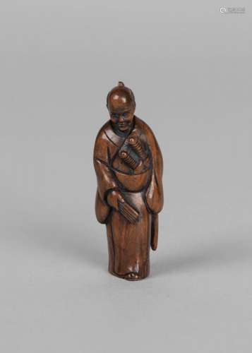 A Japanese boxwood netsuke, 20th century, carved as a samurai standing, signed to inset tab, 6cm high