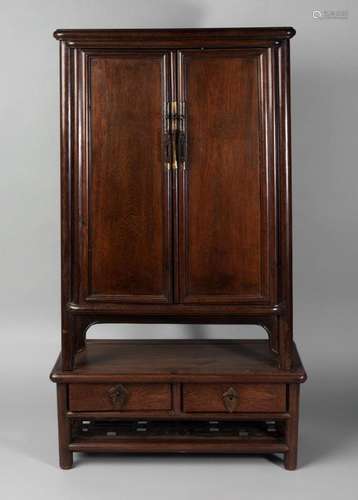 A Chinese hongmu table top cabinet on stand, 18th/19th century, with pair of cupboard doors enclosing two shelves and two base drawers, the base section with two drawers above geometrically carved undertier, 77cm x 40cm x 18cm