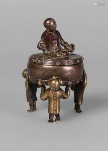 A Chinese bronze censer, Ming Dynasty, 17th century, modelled as three boys holding a drum aloft, with a boy reading atop the cover, 11cm high