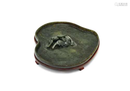 A Chinese spinach jade shallow brushwasher, 18th/19th century, shaped as a peach, carved in deep relief with two bats, on fitted hardwood stand, 14.5cm wide Provenance: Paper label for Spink & Son to base