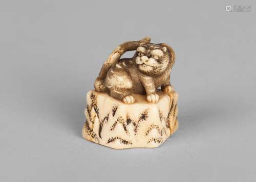 A Japanese marine ivory okimono, mid 19th century, carved as a tiger crouching on a stump, 3.6cm high