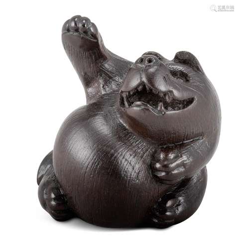 NETSUKE: TANUKI. Japan. Edo-Zeit. Spätes 18. Jh. Ebenholz, das Fell fein graviert. Das sitzende Tier