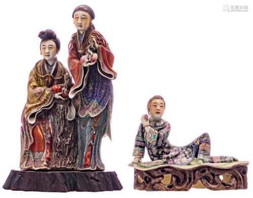 A Chinese polychrome decorated group depicting two ladies holding peaches and pomegranates on a matching wooden base; added a ditto laying figure holding a flower and a fan, marked, about 1900, H 17 - 35 - W 22 - D 10 - 19 cm