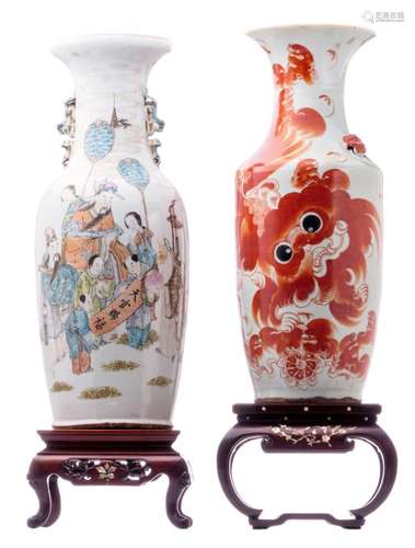 A Chinese polychrome decorated vase, one side with an animated scene and one side with antiquities and flower branches, 19thC; added a Chinese iron red decorated vase with Fu lions and calligraphic texts, 19thC, H 58 - 61 cm; extra added two Chinese carved wooden soccles with mother of pearl inlay and a marble top, H 15 - 19 cm