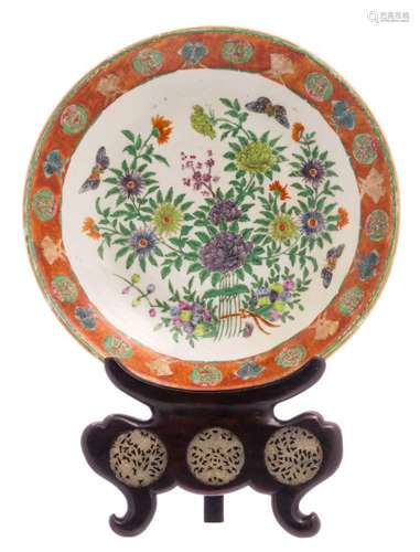 A Chinese polychrome decorated plate with flower branches, fish and butterflies, 18thC, on a matching hardwood soccle with three sculptured jade plaques depicting flower branches, a scroll and a bat, ø 37,5 cm