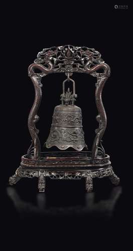 A large bronze bell with dragons and phoenixes on a wooden  ...