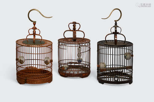 A group of three bamboo bird cages with porcelain feeders