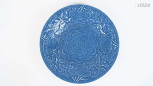 Plat rond en porcelaine émaillée bleu lavande, à décor floral moulé sous couverte. <br/>Chine, vers 1900.