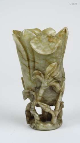 Vase en jade céladon, partiellement veiné de brun, en forme de fleur de lotus reposant sur des branchages ajourés. <br/>Chine XVIII ème - XIXème, période Jiaqing. <br/>H. 15,5 cm<br/>600/800