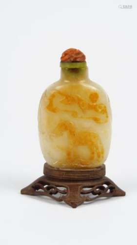Flacon tabatière en jade veiné de rouille, décor d'un cheval et d'un lion bouddhique, bouchon en corail.<br/>Chine, XIX ème siècle.<br/>H. sans le bouchon : 6 cm