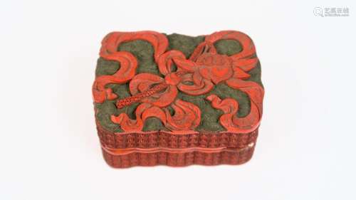 Boite couverte rectangulaire à bord polylobé en laque de cinabre finement sculpté de lotus et de motifs de passementerie.<br/>Chine, XVIII ème siècle. <br/>Dim. 3,5 x 7 x 5 cm<br/>(Petits accidents)<br/>300/400