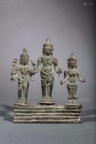 Trilogie illustrant Vishnu, Uma et Shiva sur un socle quadrangulaire, vêtu de sampots et coiffés de tiares mukutas, parés de joyaux et tenant des attributs tantriques. Bronze à patine de fouille. Khmer. Cambodge. Baphuon. 11 ème siècle. Ht 16cm x L 13cm.