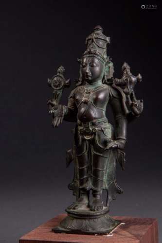 Vishnu debout dans une posture hiératique sur un piédestal lotiforme sous une forme à quatre bras, coiffé d'une haute tiare Mukuta vêtu d'un dhoti plissé paré de joyaux tenant le çakra roue de la loi et la conque çanka. Bronze. Inde du Sud. 18 ème siècle. Ht15cm.