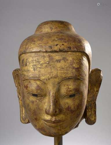 Tête de Buddha à la beauté juvénile coiffée de la protubérance crânienne ushnisha. Pierre grès beige laquée et dorée. Birmanie. Royaume d'Ava. 19 ème siècle. 40cm.