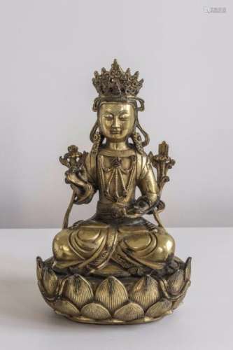Kwan Yin ou le  Boddhisattva Avalokitésvara, Buddha de la compassion, assis en dhyanasana sur un haut socle lotiforme vêtu de la robe monastique, paré de joyaux et d'un diadème incorporant l'image du Buddha Amitabha son hypostase, tenant la branche de lotus grimpant d'une main prêchant la doctrine en virtaka mudra et de l'autre main les tablettes des utra également sur une branche de lotus. Bronze doré au mercure. Chine dynastie Qing. 19 ème siècle.  Au verso une marque apocryphe de l'Empereur Yongle.  Ht 25,5cm.