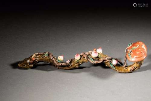 Sceptre Ruyi en porcelaine de la famille rose modelé en trompe l'œil d'un bâton noueux parsemé de symboles de longévité : pêches, champignon Lingzhi et chauve souris décoré en émaux polychromes. Ce type de ruyi était utilisé comme talisman symbolisant le pouvoir et al bonne fortune.  Chine. Dynastie Qing.  Long: 35 cm. Ancienne collection de Mr Roger meffreys ambassadeur de France en Chine de 1936 à 1946