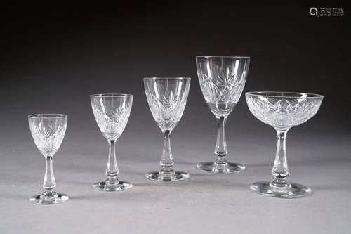 Service de verres “Lubin“. Cristal incolore taillé d'épis. Jambe cintrée et pied rond. Il présente douze verres à eau, douze coupes à champagne, onze verres à porto, douze grands et douze petits verres à vin. Au total: cinquante-neuf pièces.