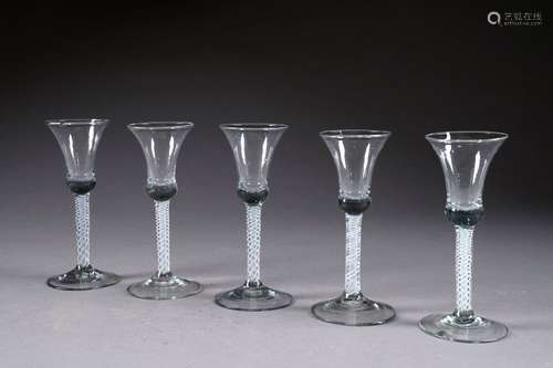 Suite de cinq Verres à Vin. Jambe à latticini. Verre soufflé blanc et incolore. XVIIIe siècle.<br/>Hauteur: 17,5 cm. (Deux petits éclats aux pieds).