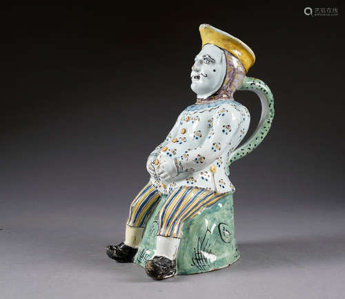 Pot Jacquot. Figurant un homme bedonnant, vêtu d'un pantalon rayé, assis sur un tertre. Faïence polychrome. Lille. XVIIIe siècle.<br/>Hauteur: 33 cm. Condition: Egrenures. Petite restauration au pied droit.