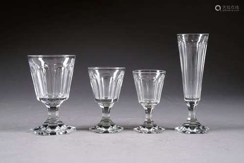 Service de verres pour douze personnes. Il présente douze flûtes à champagne, douze verres à eau, douze verres à vin blanc et douze verres à vin rouge. Pied hexagonal et jambe cintrée. Epais cristal incolore taillé de côtes plates. Au total: quarante-huit pièces.