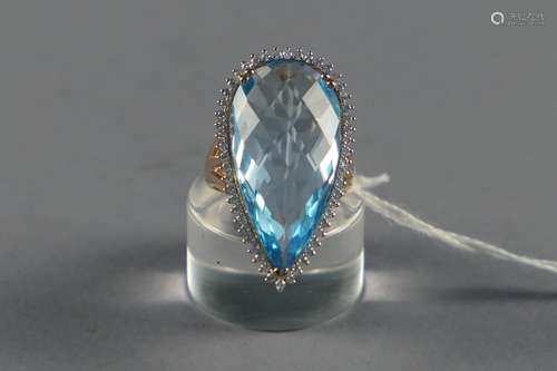 Importante Bague de Dame “Entourage“. Sertie d'une topaze bleue taille briolet (env. 26 carats 23) rehaussée de cinquante-deux diamants taille brillant (env. 0 carat 50). Monture en or jaune 18 carats.<br/>Poids: 11,9 g. Taille: 55.